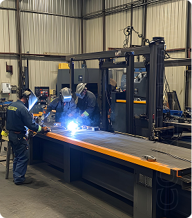The image depicts a metal fabrication workshop where workers are engaged in welding. Fabrication is the process of constructing items from raw materials, typically metals, using methods like cutting, bending, and joining.